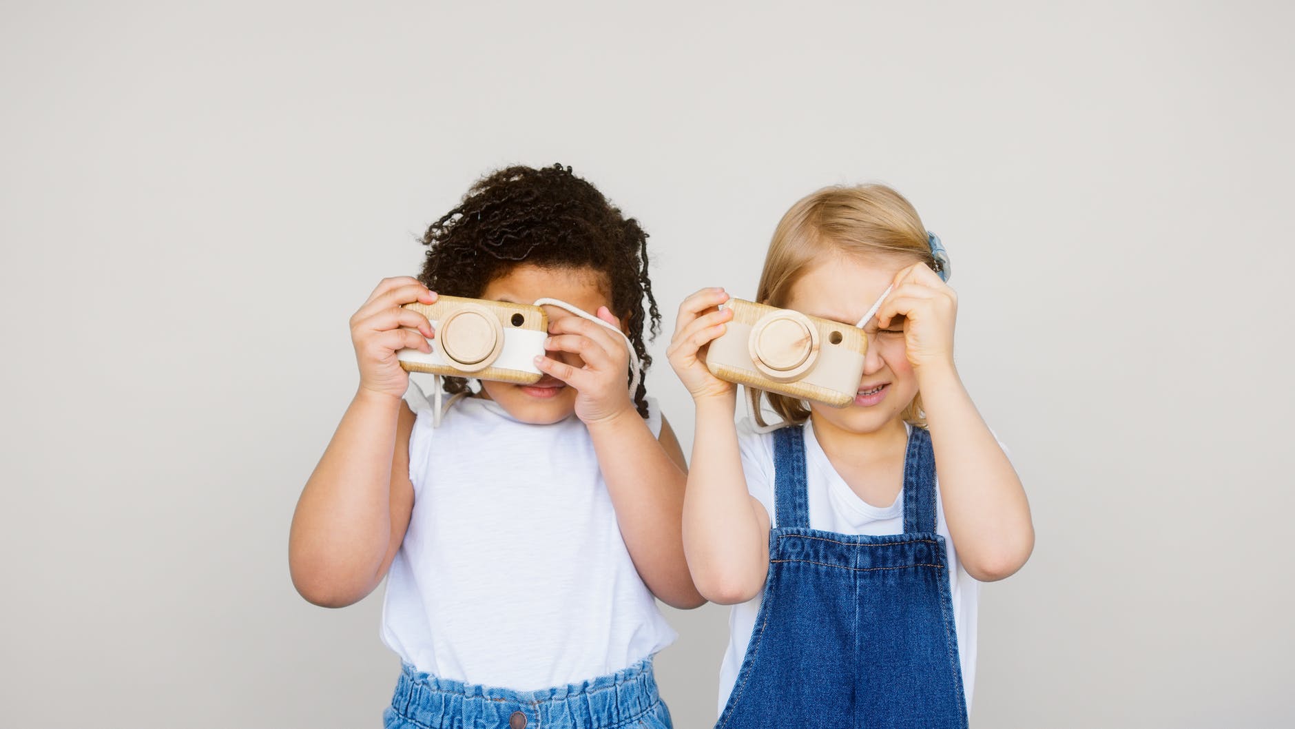 two kids taking photo using a camera